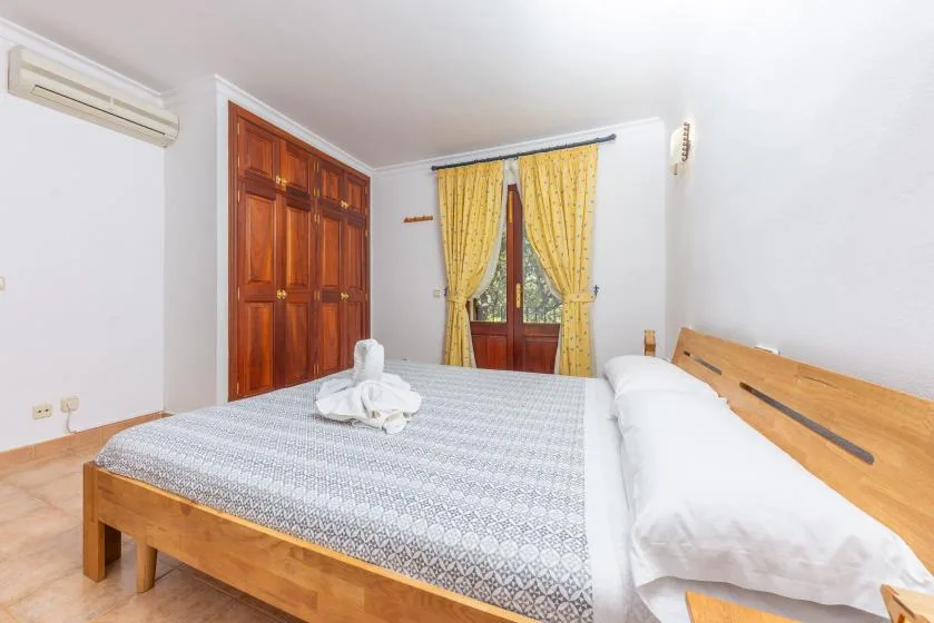 Un dormitorio con una cama de madera y cortinas amarillas en la ventana.