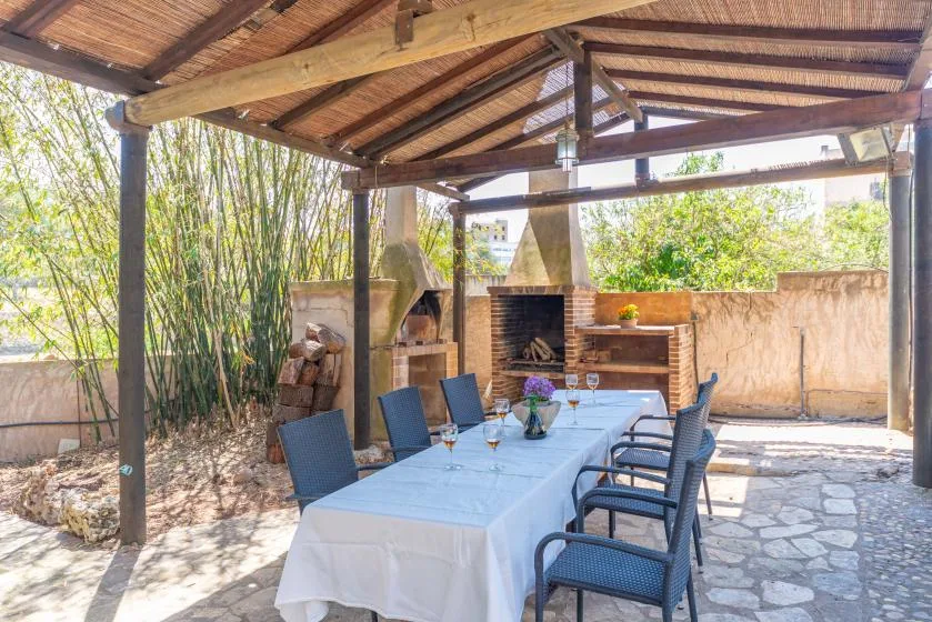 A covered outdoor dining area with a long table and built-in barbecue.
