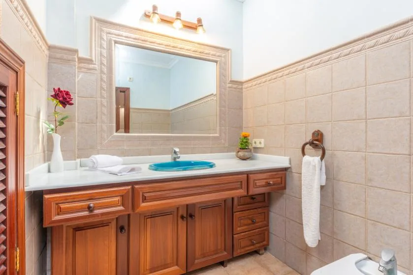 Un tocador de baño con un espejo amplio, paredes de azulejos y una toalla colgada cerca.