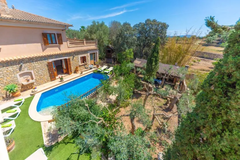 A Mediterranean-style house overlooks a swimming pool and landscaped garden.