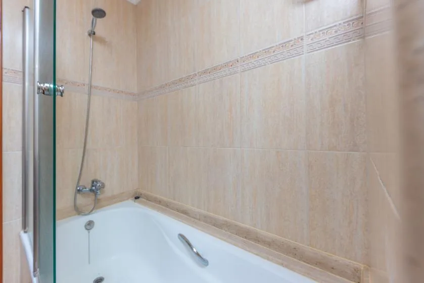 Un baño con azulejos, bañera y ducha de pared.