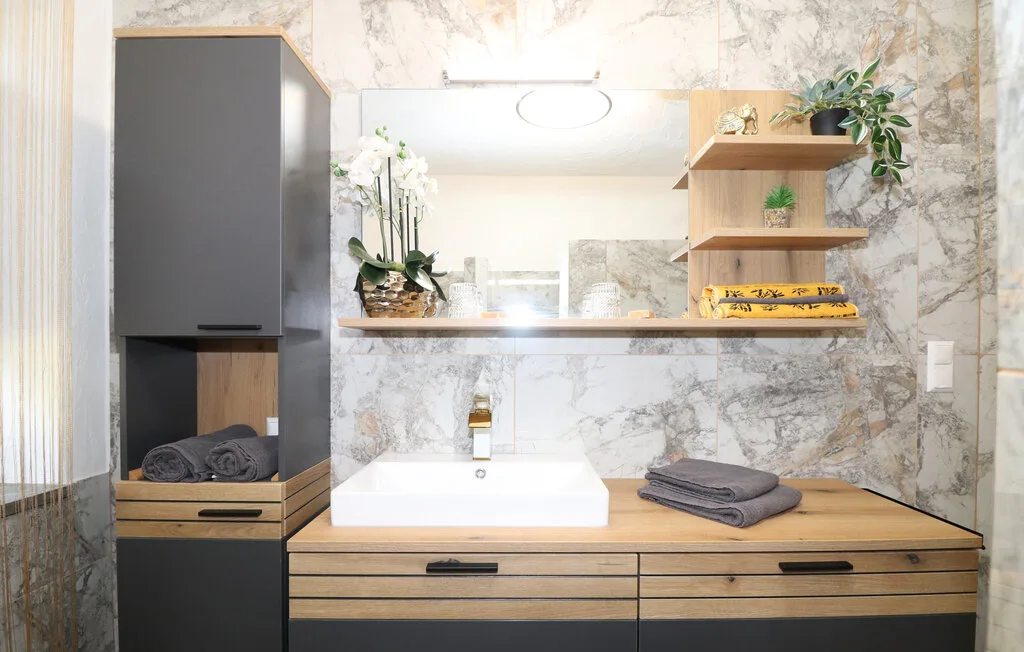 Un tocador de baño con un espejo amplio y estantes abiertos de madera.