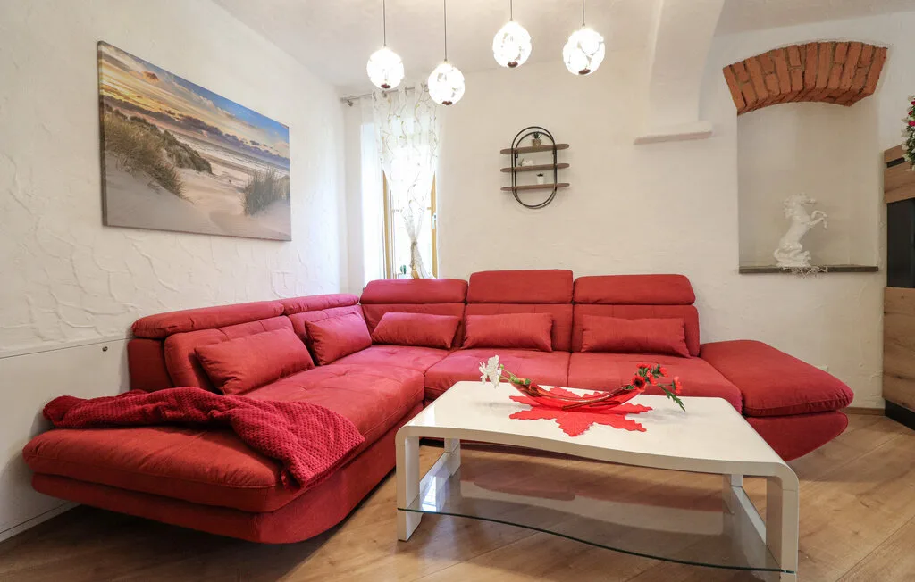 Una sala de estar con asientos rojos y una mesa de centro blanca.