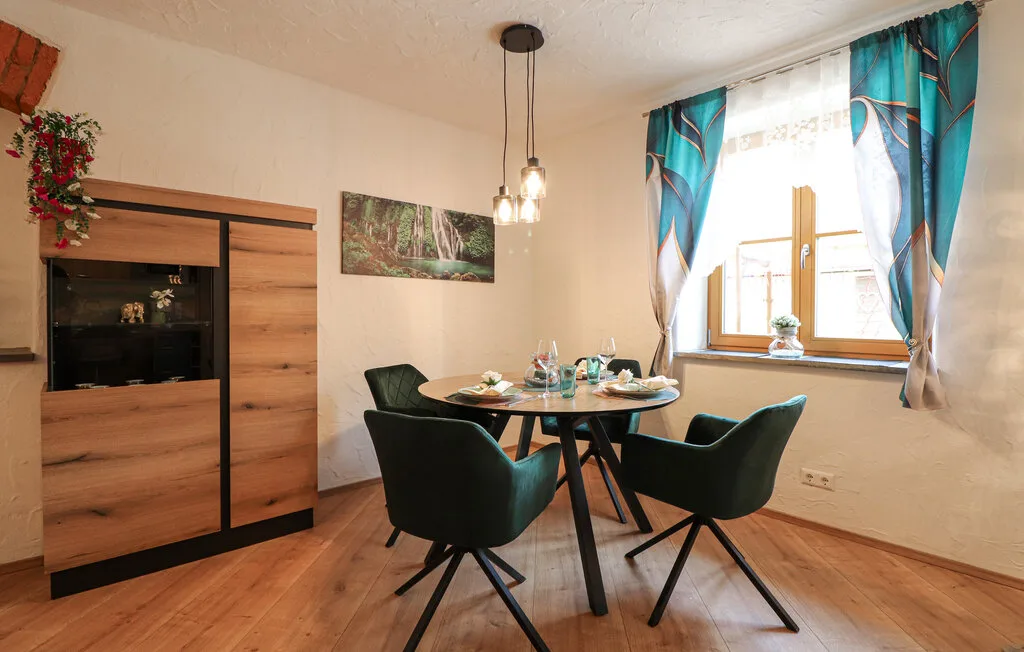 Un comedor con una mesa redonda y asientos oscuros junto a una ventana luminosa.
