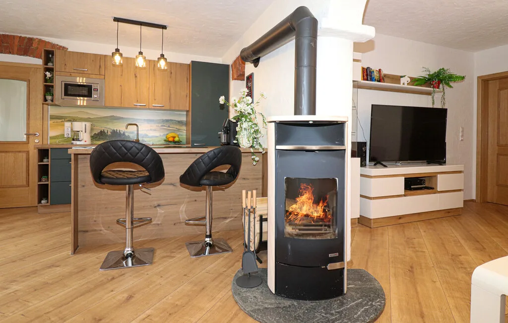 An open-plan living room and kitchen with a freestanding fireplace.