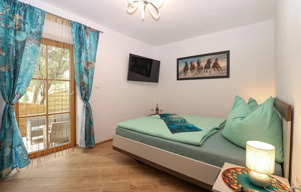 Un dormitorio con una cama, cortinas turquesas y cuadros enmarcados.