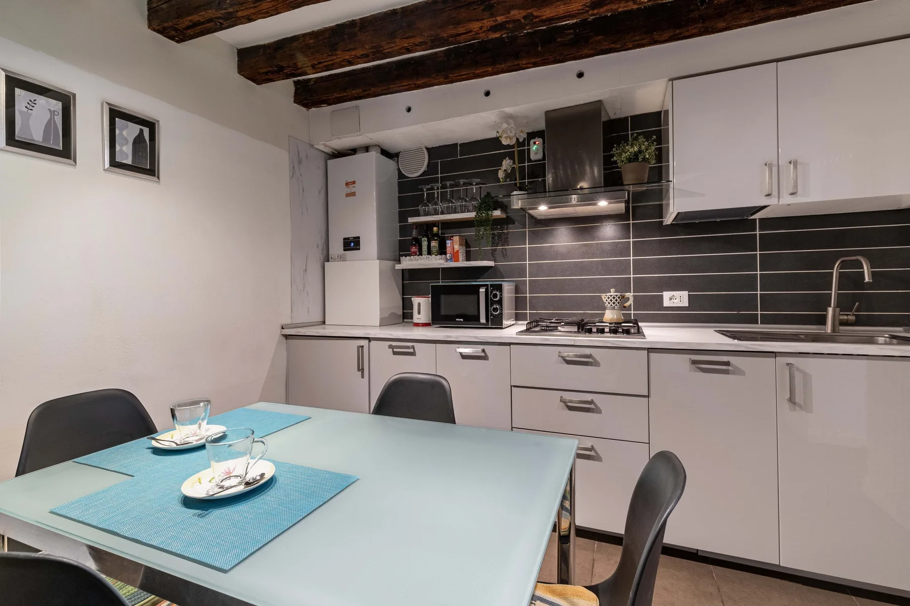 A kitchen and dining area with a table in the foreground and cabinets along the wall.