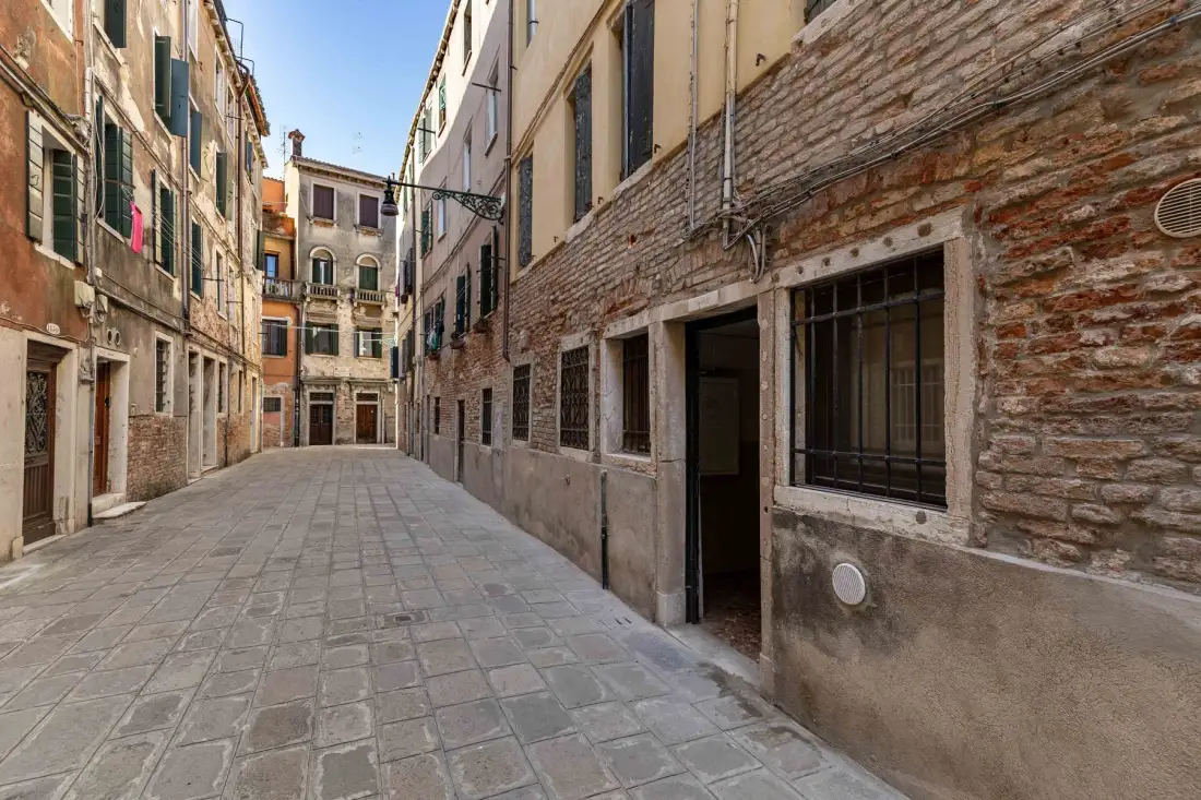 A narrow paved lane runs between closely spaced buildings.