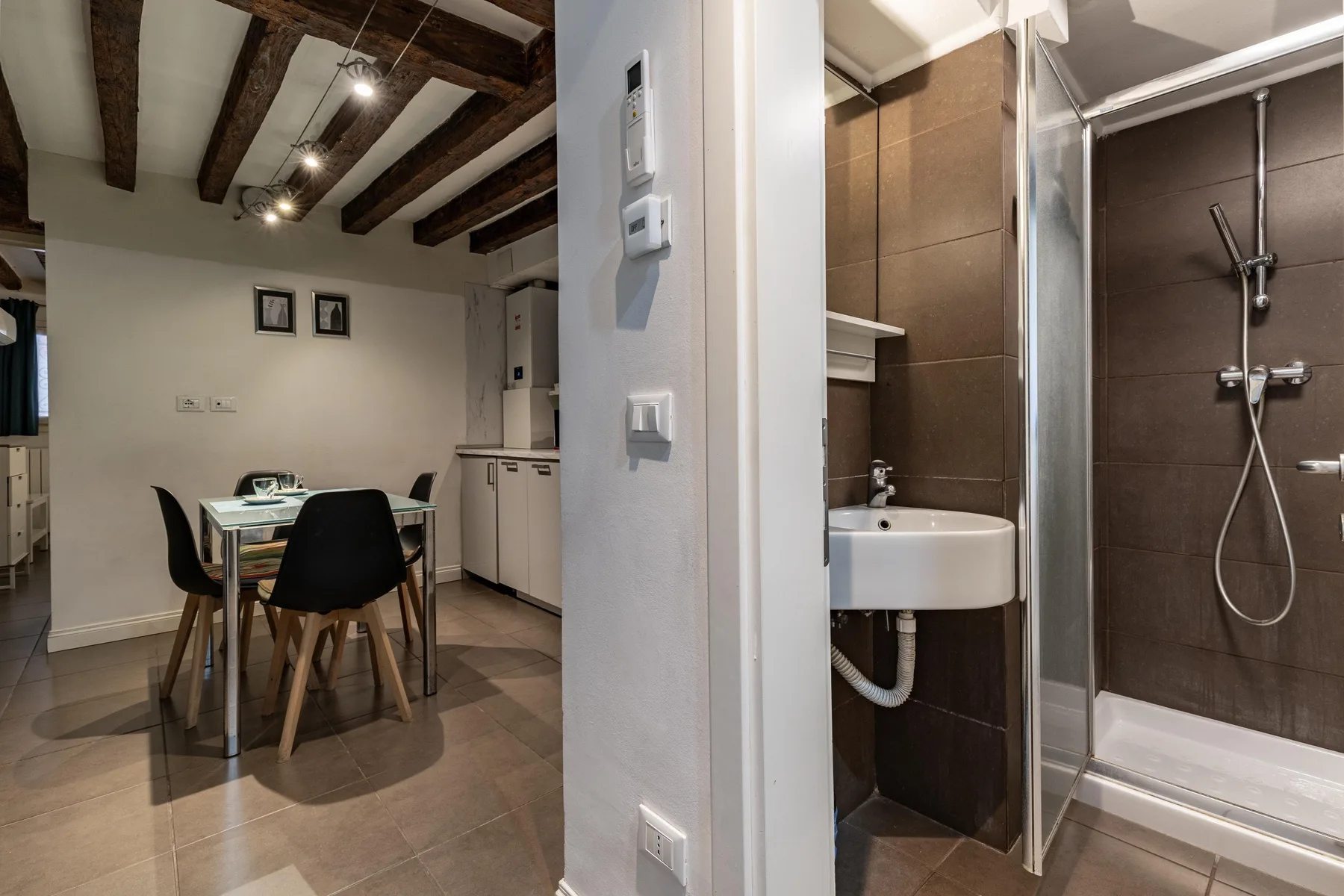 A dining area with a table and chairs beside a bathroom with a shower.