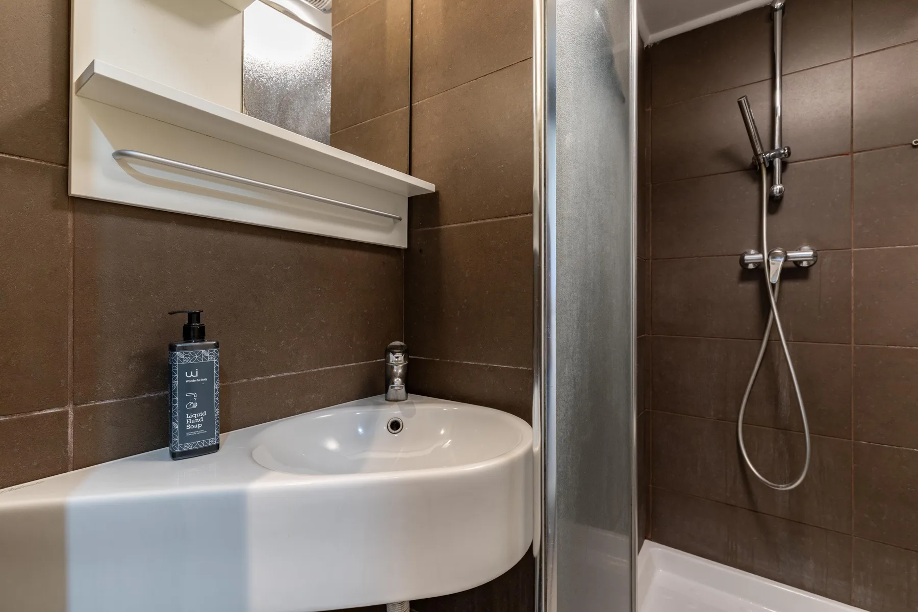 A bathroom with a white sink beside a tiled shower.
