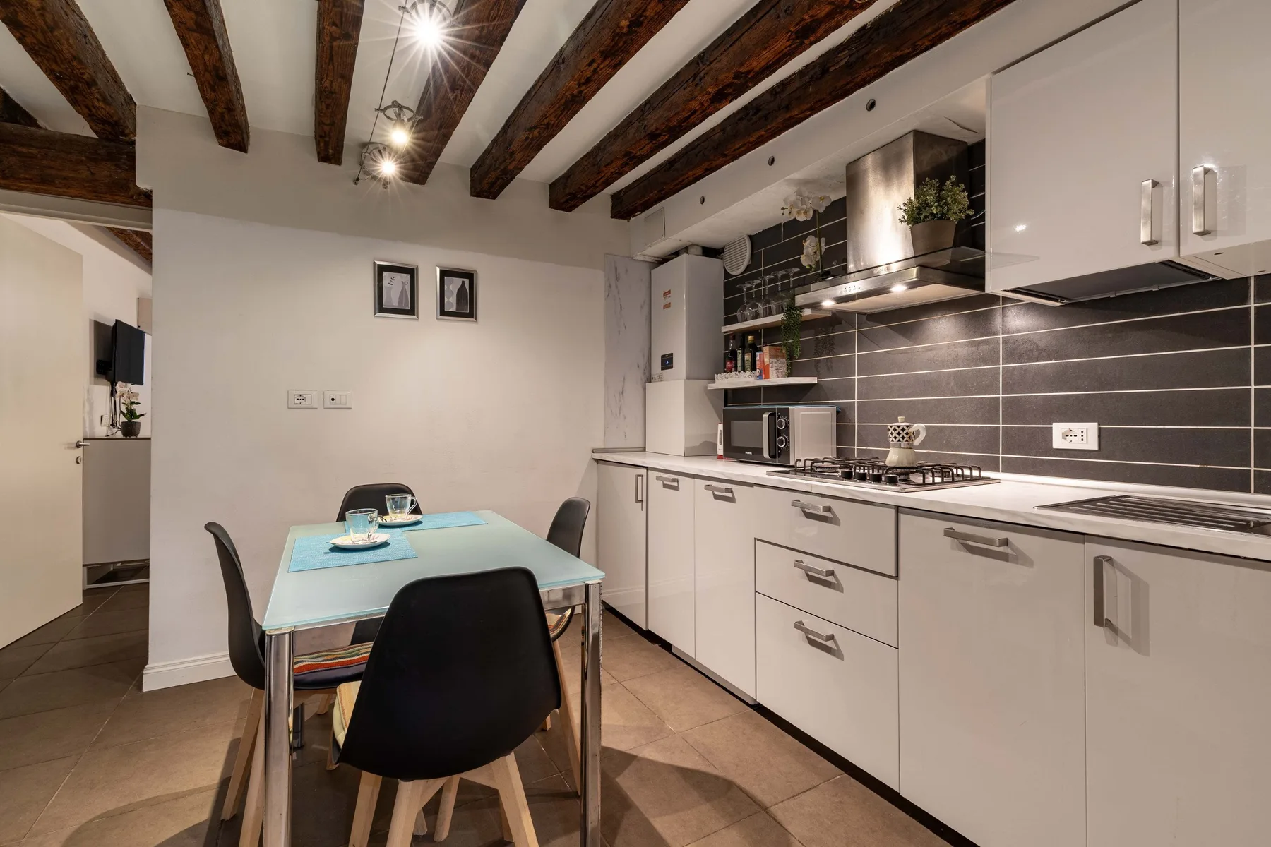 Una cocina compacta con una mesa de comedor y sillas oscuras.