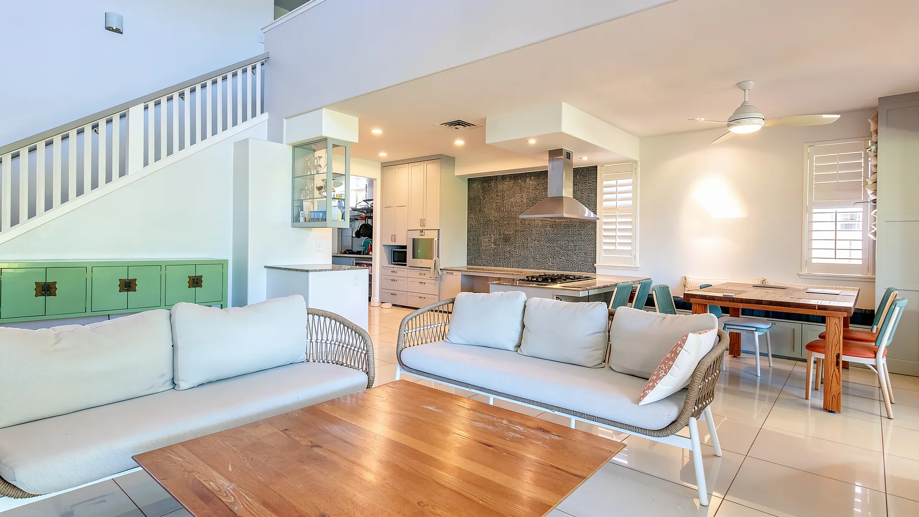 An open-plan living and dining area with seating, a wooden coffee table, and a kitchen.