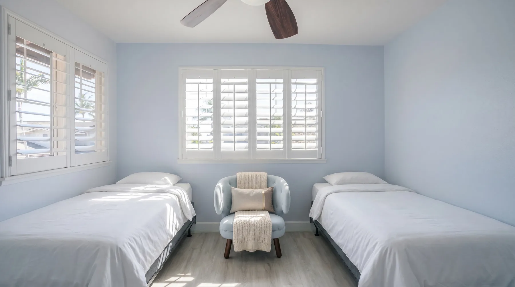 Un dormitorio luminoso tiene dos camas y una silla pequeña entre ellas.