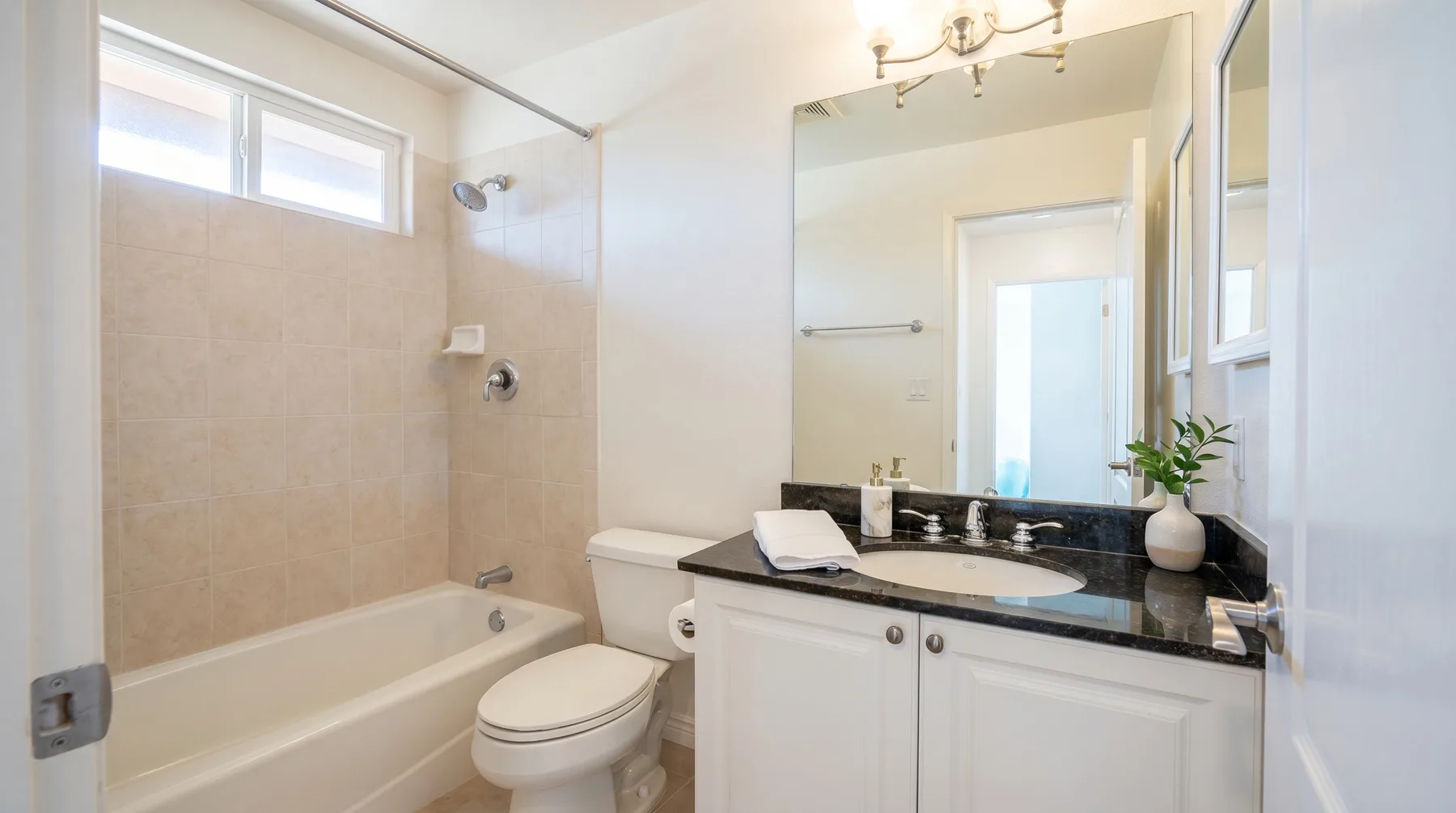 Un baño luminoso con bañera, inodoro y lavabo bajo un espejo grande.