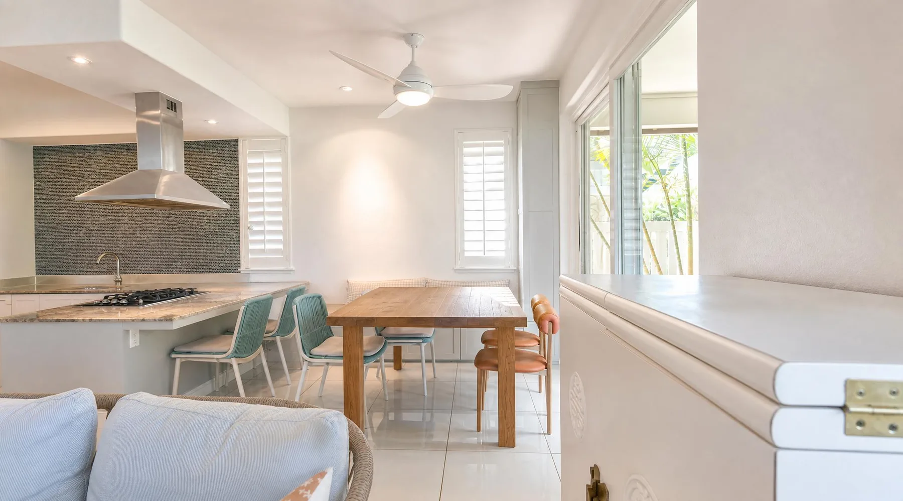 Una luminosa cocina y comedor con barra, mesa y grandes ventanas.
