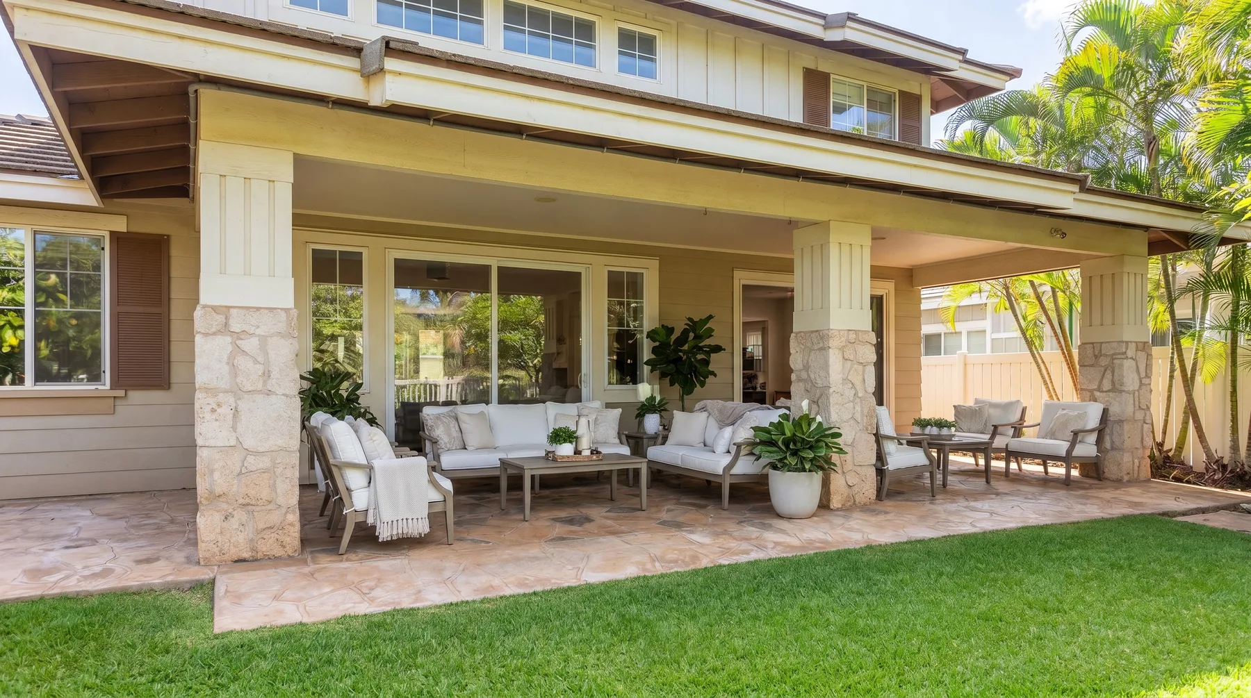 A covered outdoor patio with seating opens onto a green lawn.