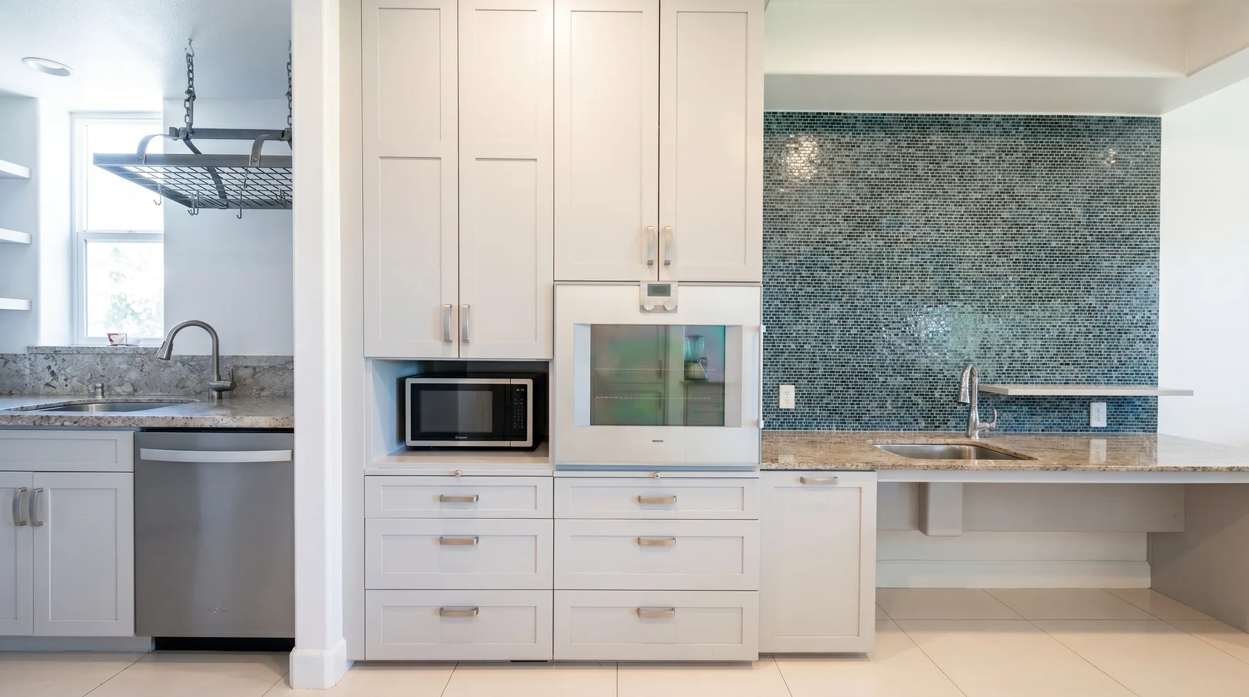 Una cocina luminosa con gabinetes blancos, un microondas empotrado y un salpicadero de azulejos.