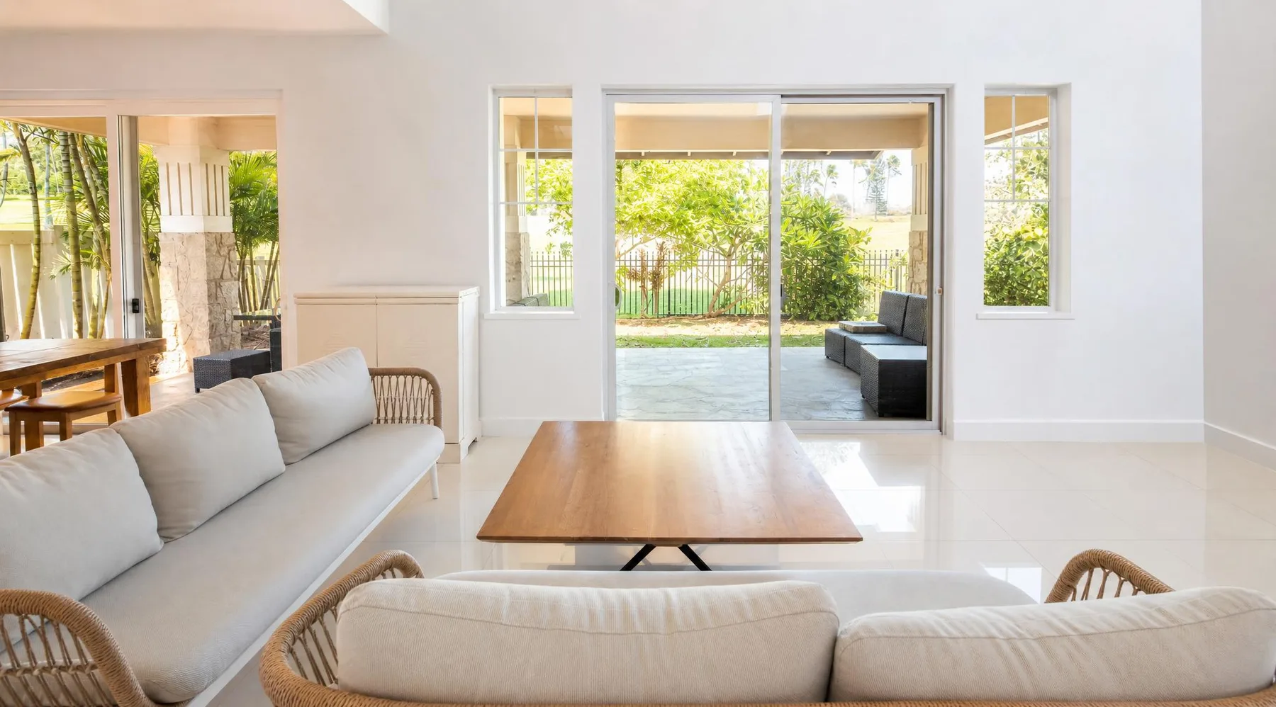 Una sala luminosa con asientos alrededor de una mesa de centro de madera y vistas al jardín.