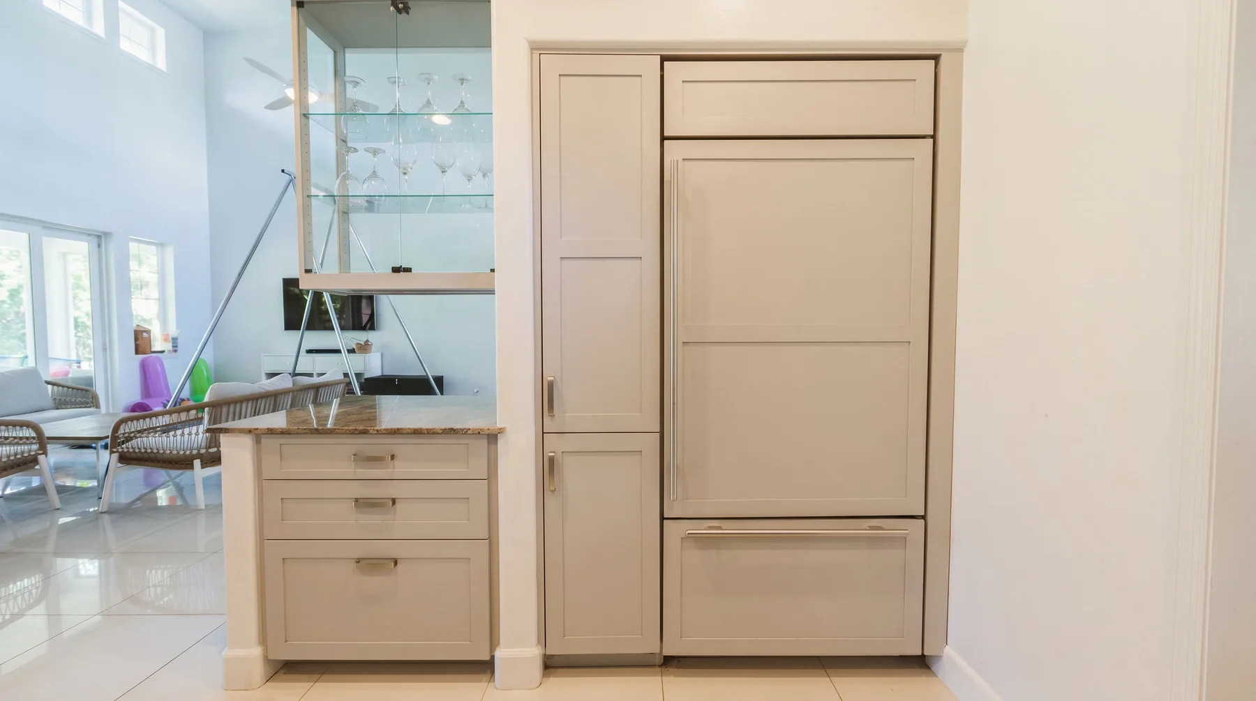 Una luminosa zona de cocina con gabinetes claros y un gabinete superior con frente de vidrio.