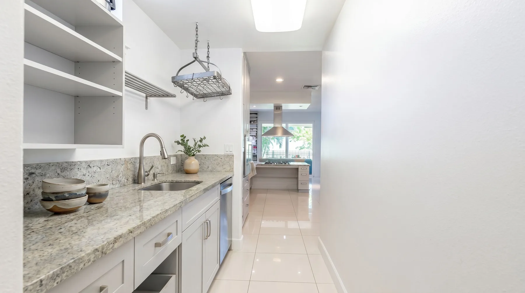 Una cocina luminosa con una encimera larga y un fregadero se abre a una sala de estar.