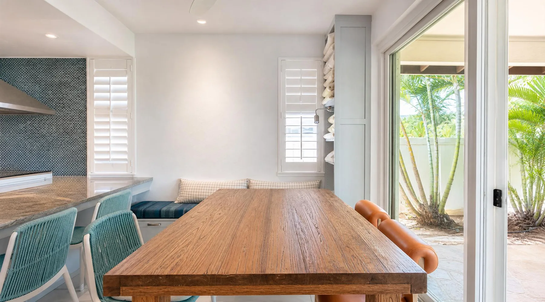 Comedor con una larga mesa de madera junto a una puerta de vidrio abierta.