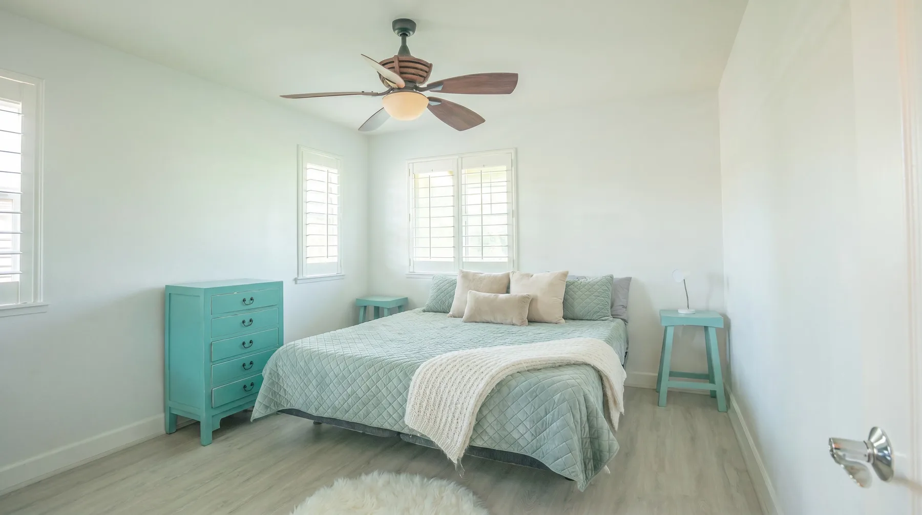 Un dormitorio luminoso con una cama y muebles turquesa.
