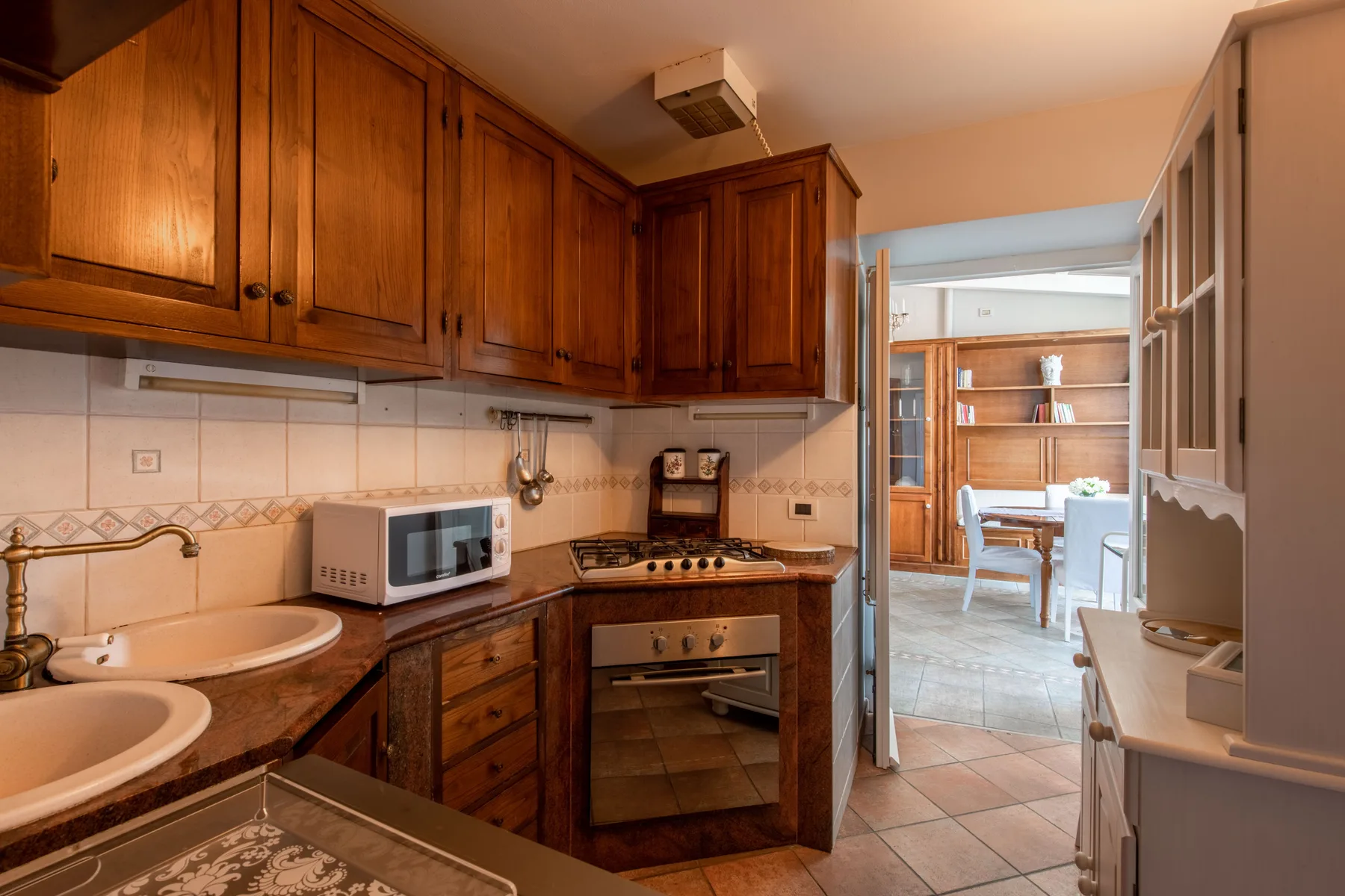 A kitchen with wooden cabinets, a cooktop, and a microwave.