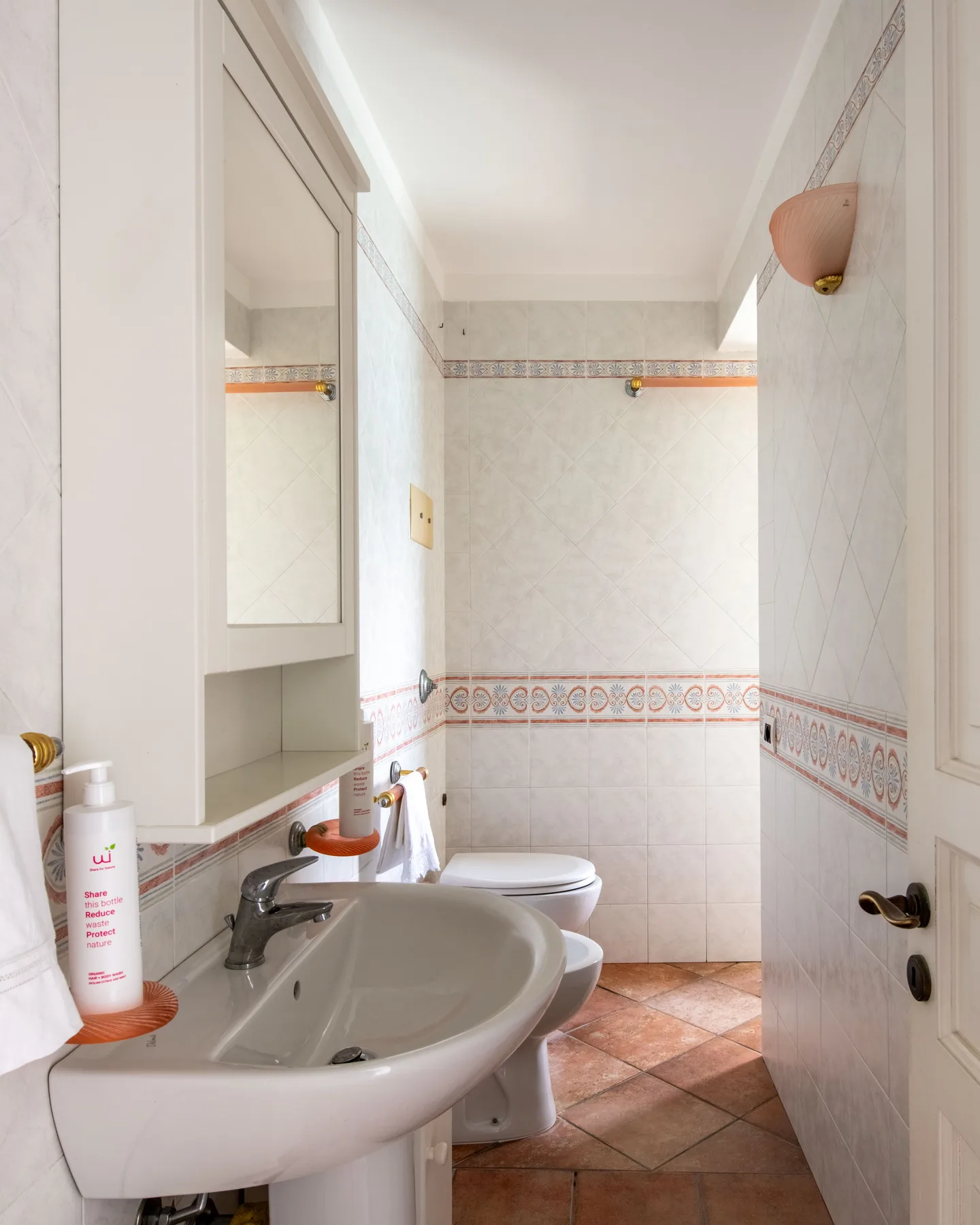 Un baño con azulejos, lavabo e inodoro.