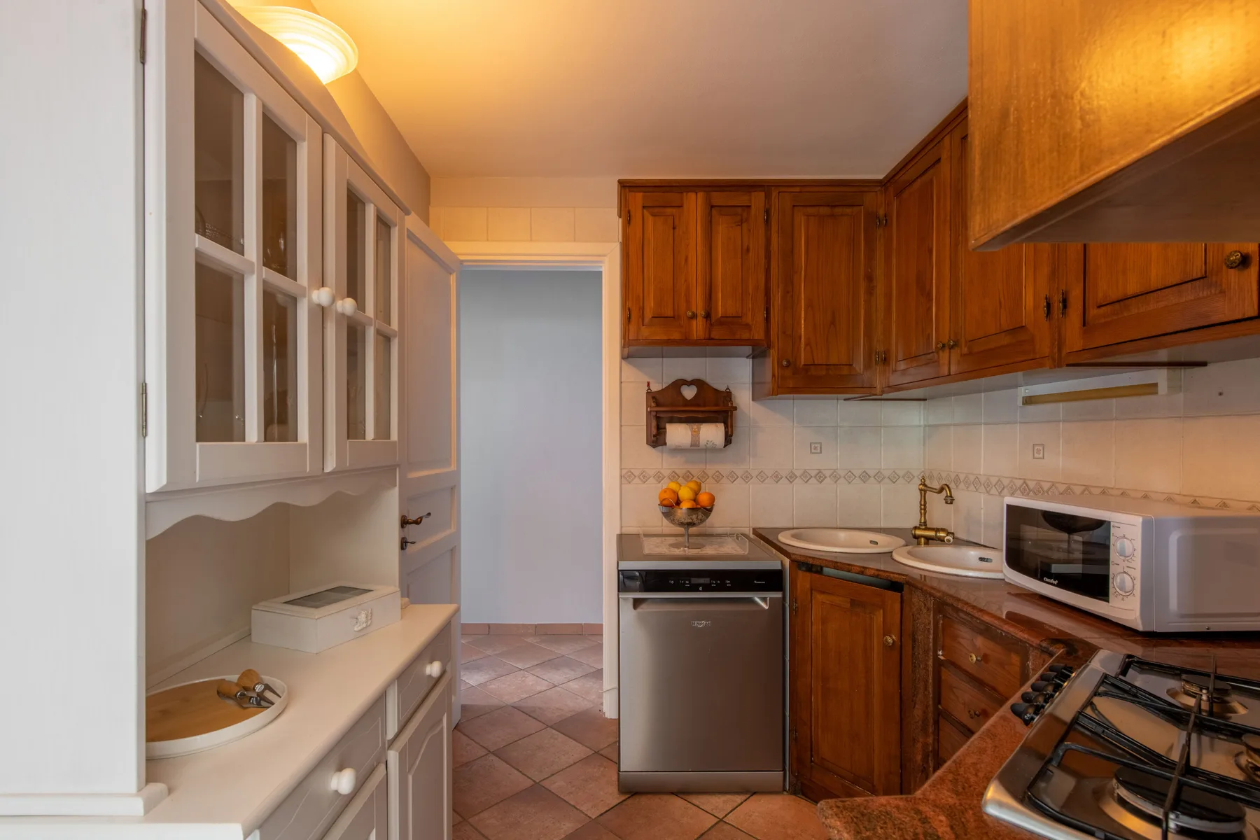 Una cocina compacta con gabinetes de madera, un salpicadero de azulejos y una encimera.