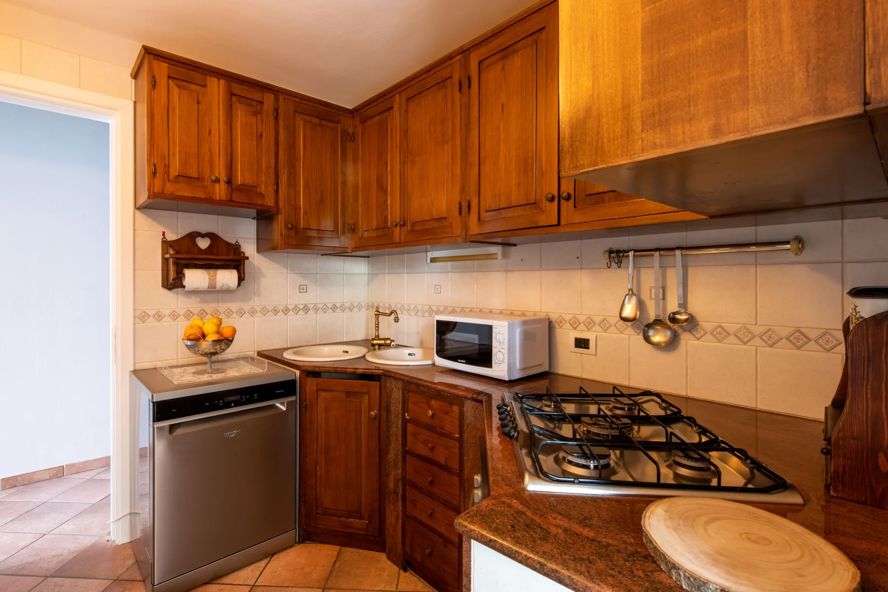 Una cocina compacta con gabinetes de madera, paredes de azulejos y una estufa de gas.