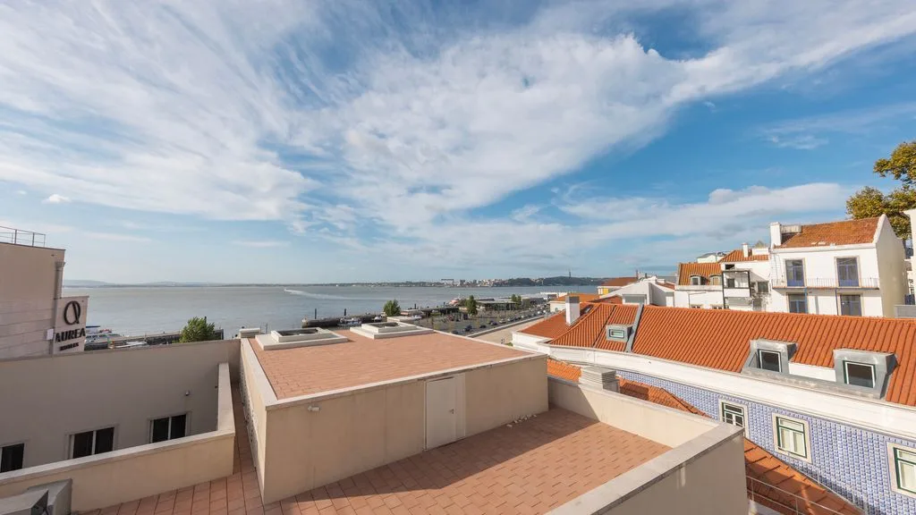 Se ven un pueblo costero y el paseo marítimo más allá de los tejados, bajo un cielo nublado.