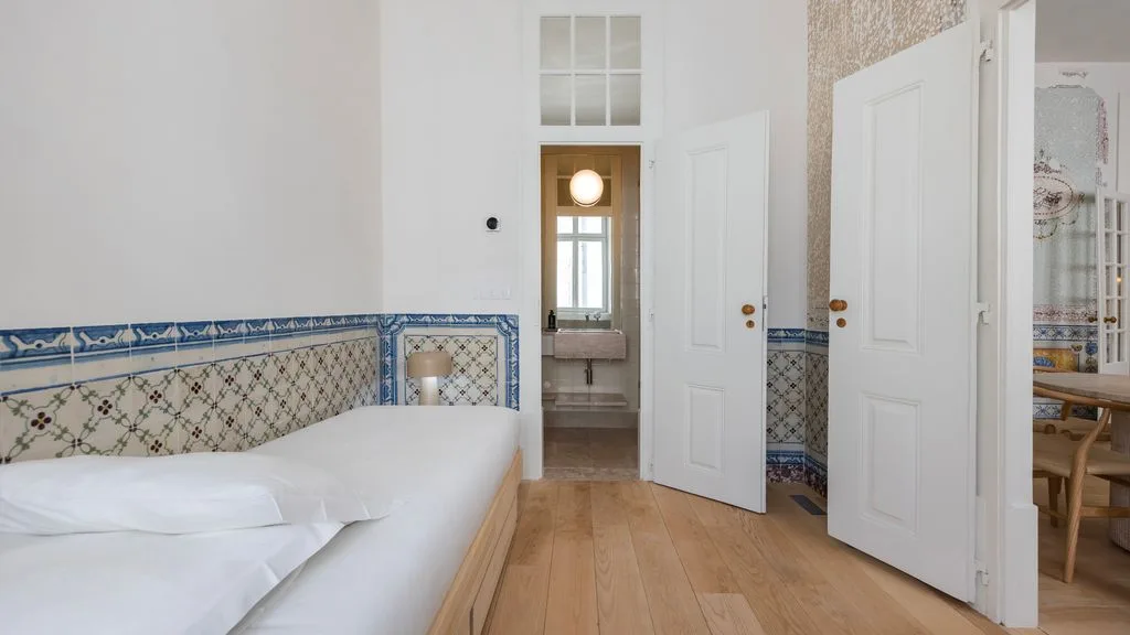 Un dormitorio con una cama junto a una puerta abierta que da a un baño.