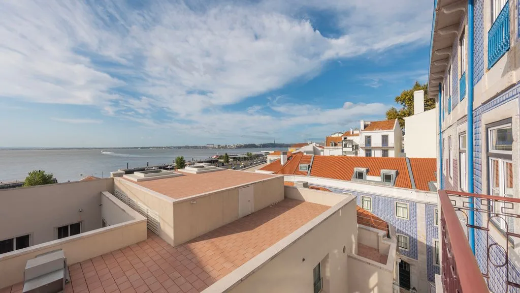 Terraza en la azotea con vistas al agua, superficies de baldosas y edificios cercanos.