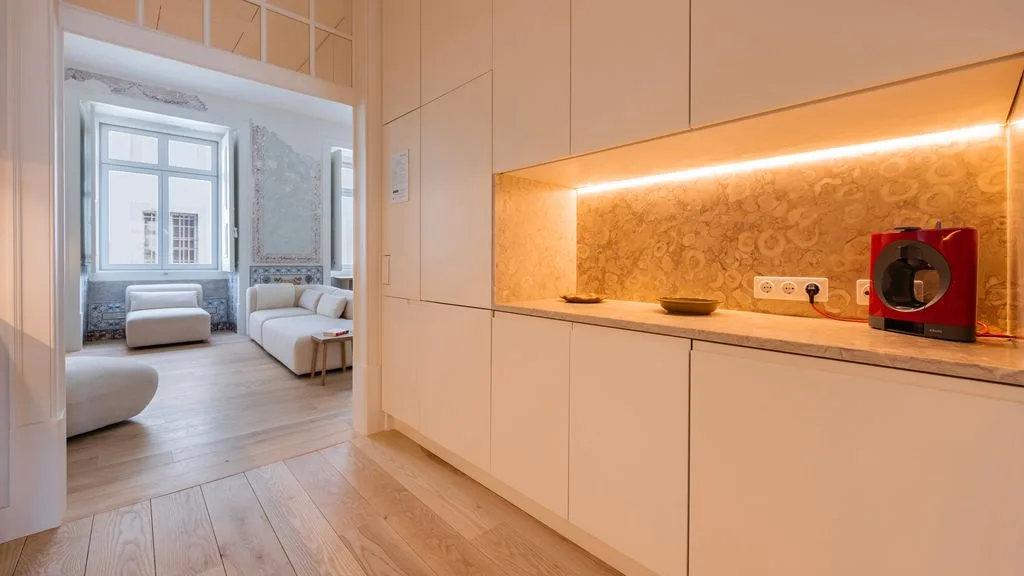 Una sala luminosa con asientos claros se ve más allá de la encimera de una cocina moderna.