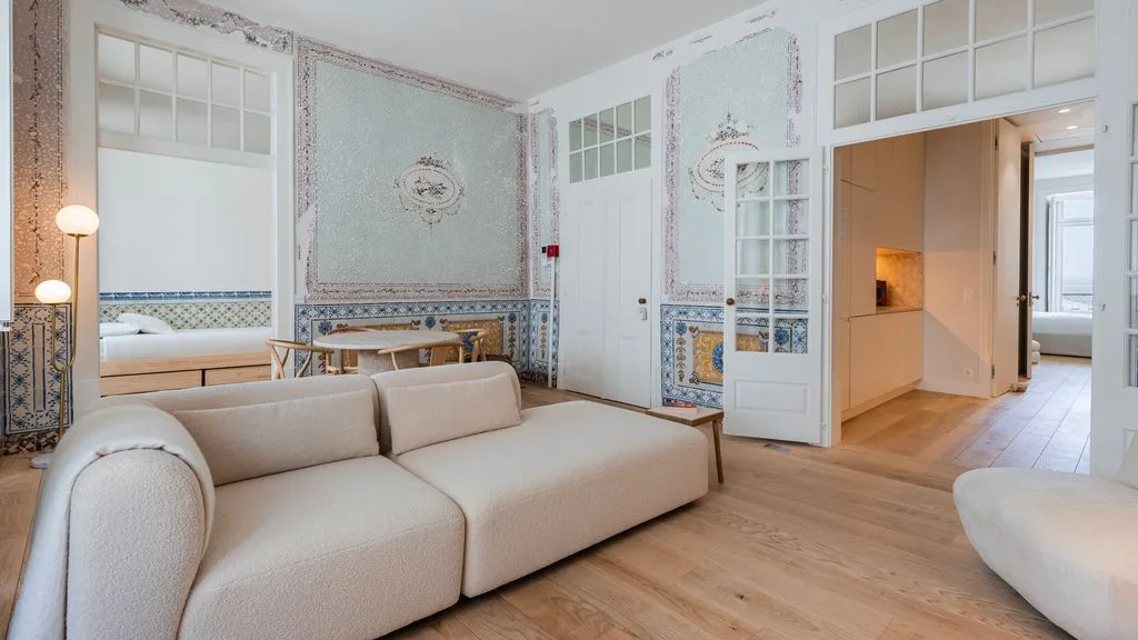 Una sala de estar con asientos claros y paredes con motivos ornamentales.