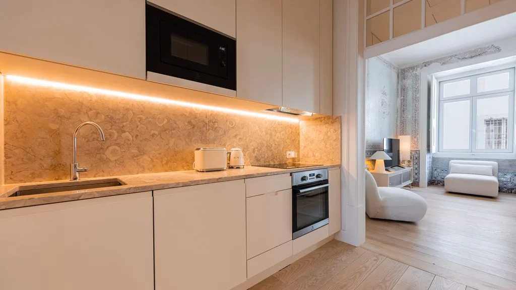 Una cocina moderna se abre a una luminosa sala de estar con grandes ventanas.