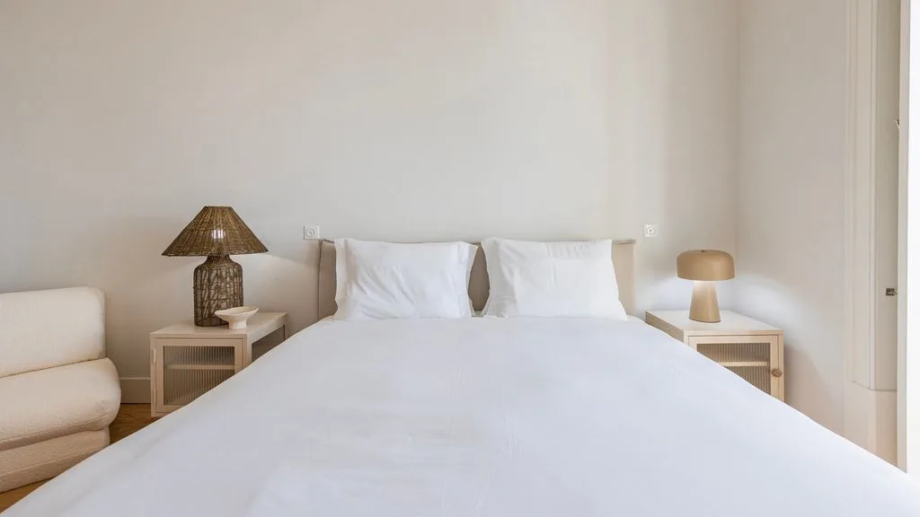 Un dormitorio luminoso con una cama tendida y mesitas de noche a ambos lados.