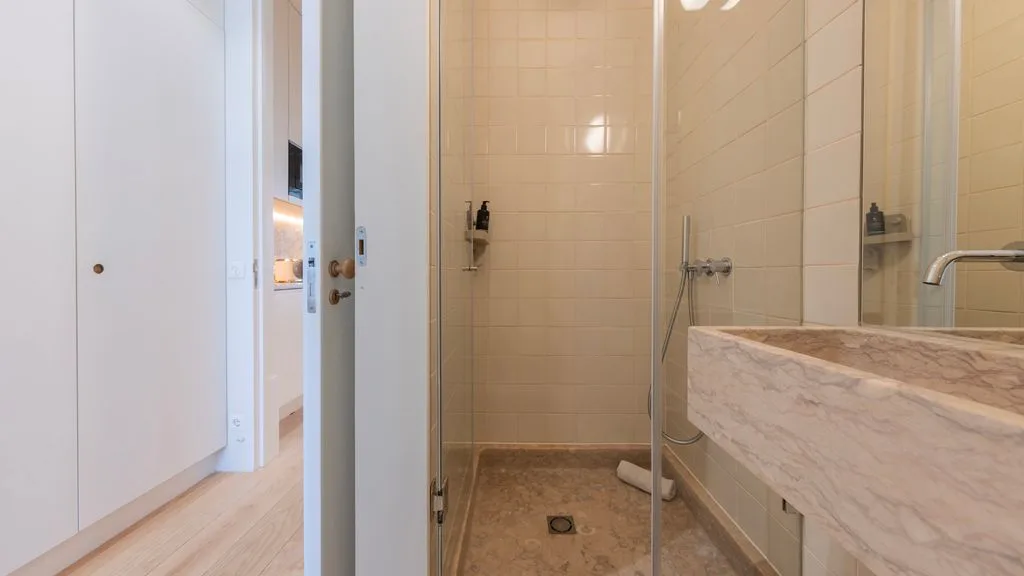 Un baño revestido de azulejos con ducha de vidrio y lavabo de mármol.