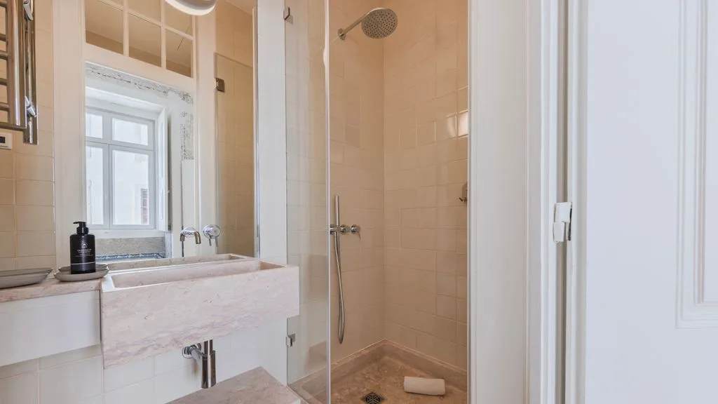 Un baño con un lavabo junto a una ducha con mampara de vidrio.