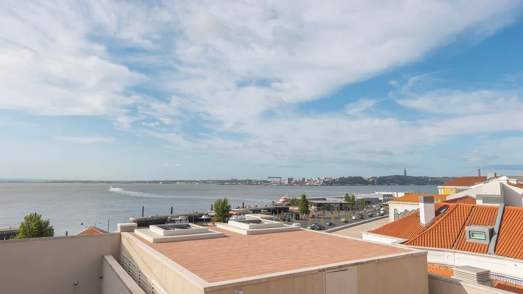 Una terraza en la azotea da al paseo marítimo y a edificios cercanos.