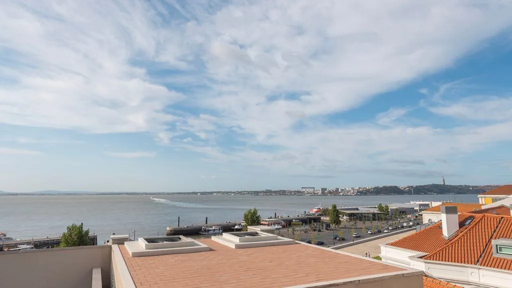 Una vista costera con una amplia bahía, edificios junto a la orilla y cielo parcialmente nublado.