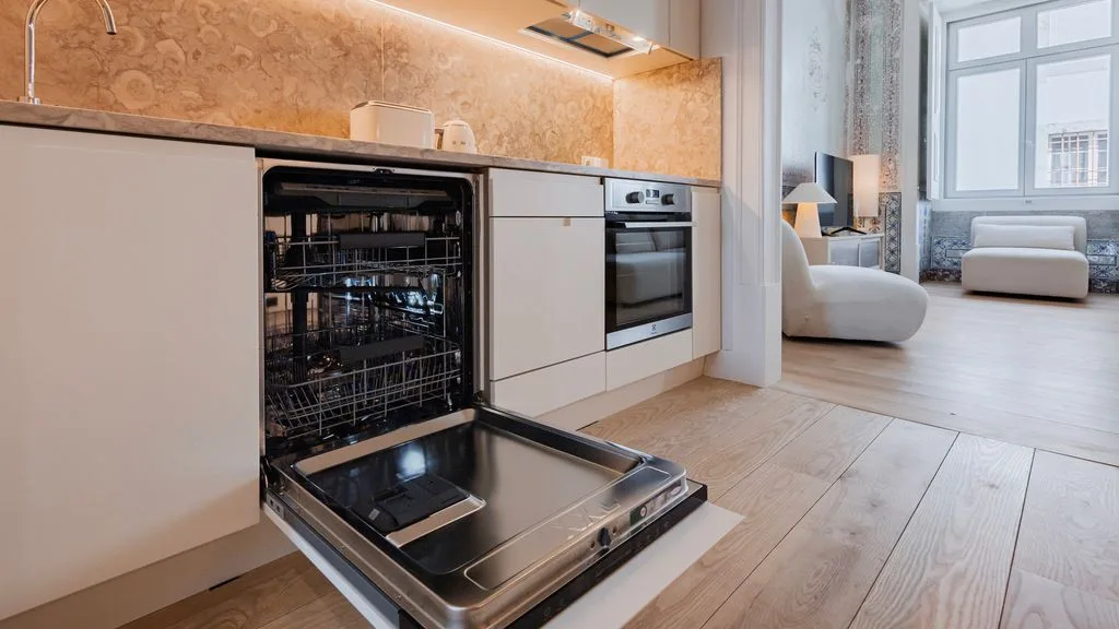 Una cocina moderna con el lavavajillas abierto y una zona de estar junto a la ventana.
