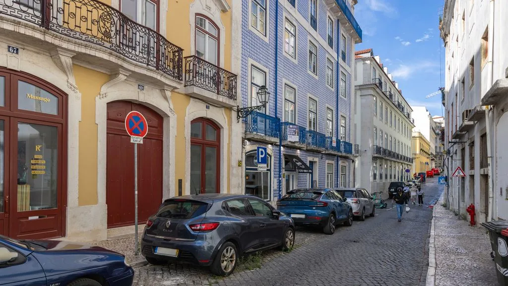 Una calle adoquinada de la ciudad, bordeada de edificios coloridos y coches aparcados.
