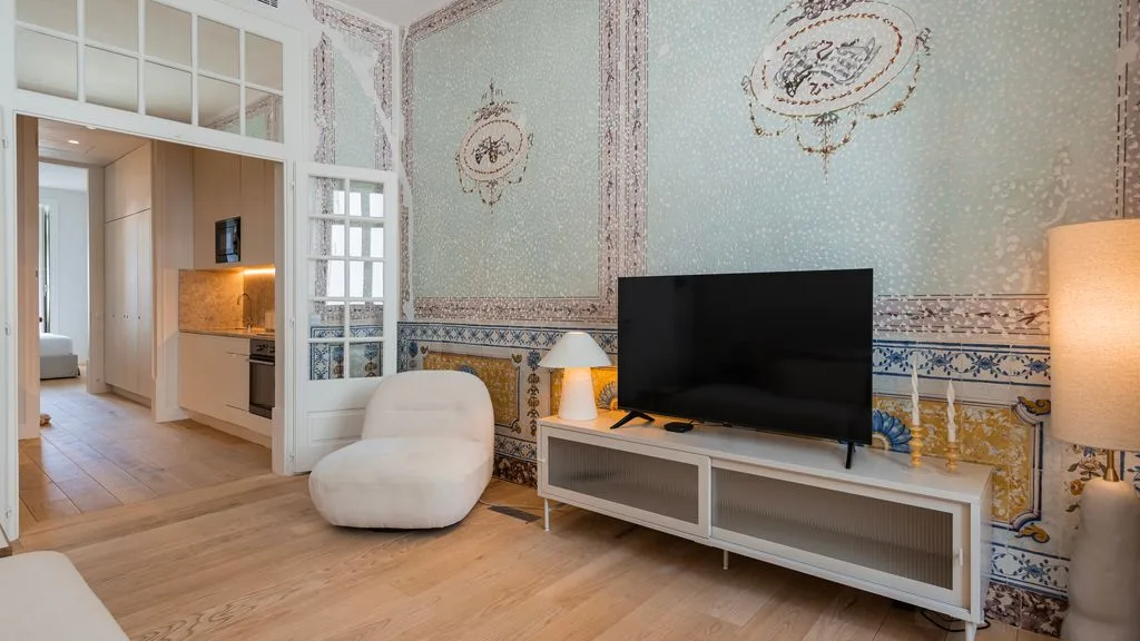 Una sala de estar con un televisor sobre una consola y paredes decorativas estampadas.