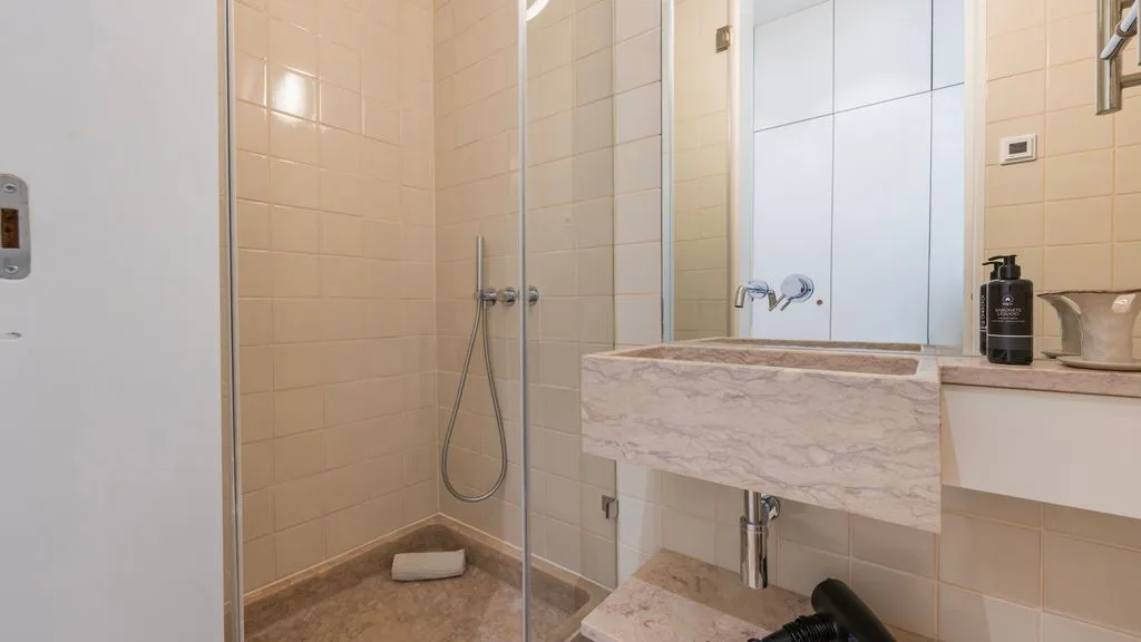 Un baño alicatado con ducha de vidrio y un lavabo de piedra.