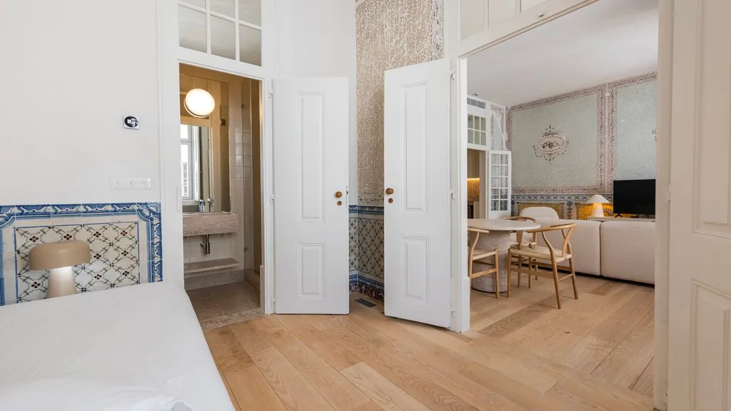 Un interior luminoso conecta una zona de baño con azulejos y un espacio de estar y comedor.