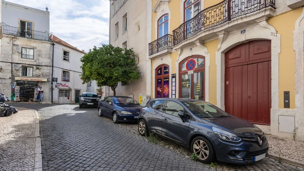 Una calle empedrada con coches aparcados y edificios de colores.