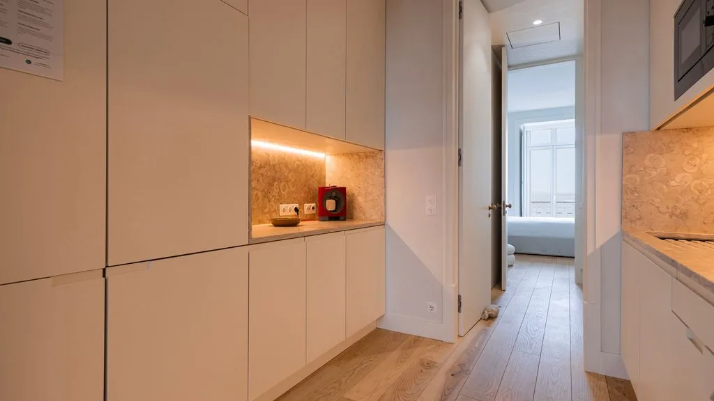 Una cocina luminosa con armarios empotrados y una puerta abierta hacia un dormitorio.