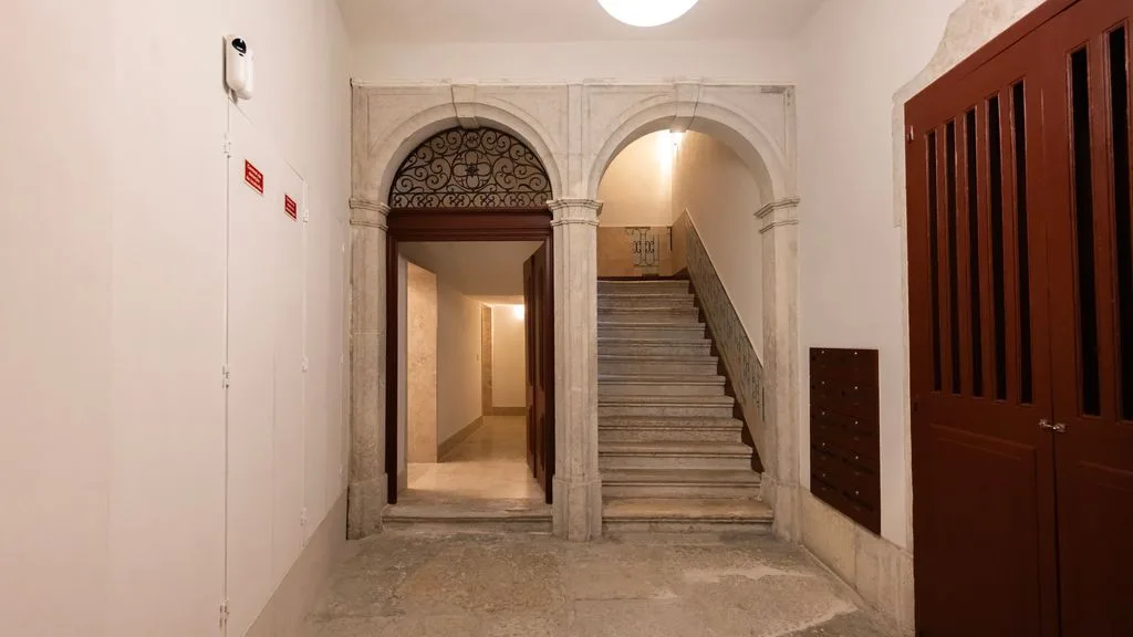 Un pasillo interior con una puerta arqueada junto a una escalera.