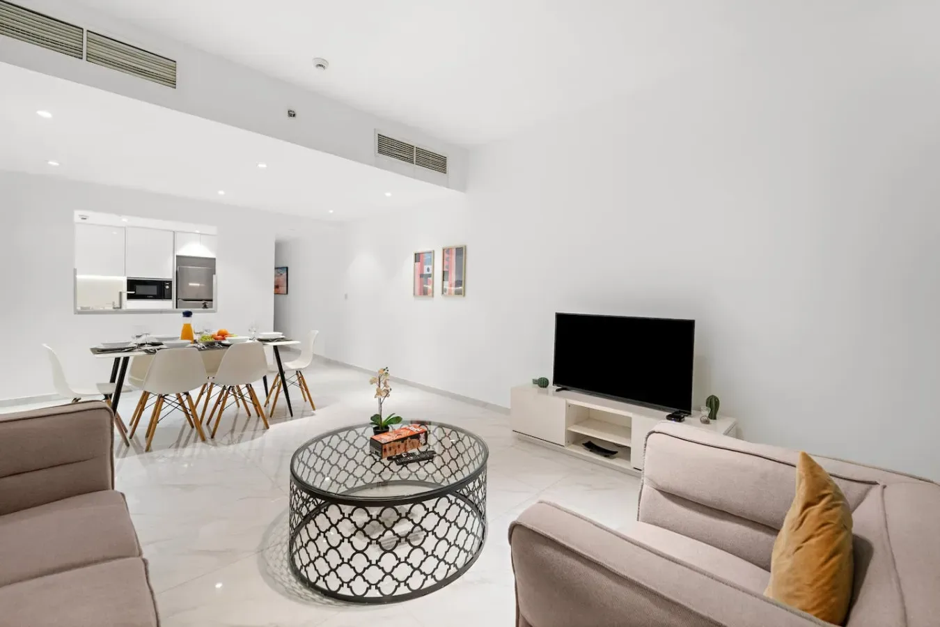 Una luminosa sala de estar y comedor con televisor y mesa de centro redonda.